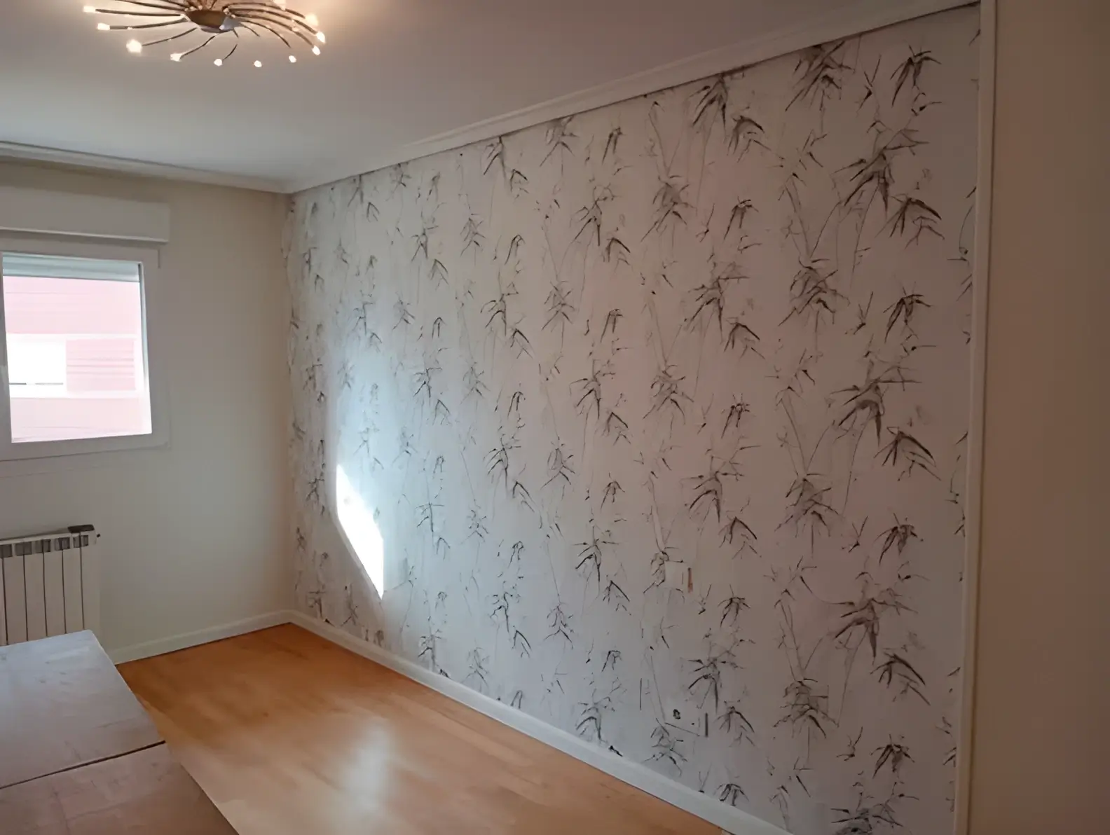 Los Pintores Móstoles colocando papel pintado en pared de acento de habitación luminosa